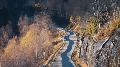 Aerial-view-of-the-narrow-rural-road-winding-through-the-autumn-landscape