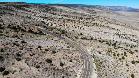 Car-drives-through-scenic-arid-landscape-along-US-Highway-89A