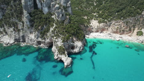 Aerial-drone-video-of-tropical-paradise-beach-and-sea-cliffs-in-the-mediterranean,-Cala-Goloritzè,-Sardinia,-Italy