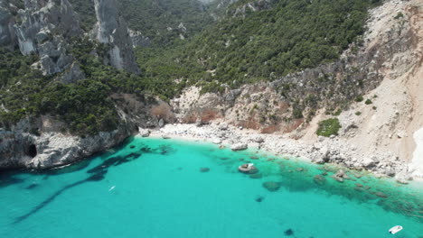 Aerial-drone-video-of-tropical-paradise-turquoise-beach-and-sea-cliffs-in-the-mediterranean,-Cala-Goloritzè,-Sardinia
