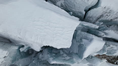 Aerial-close-up-view-of-the-crevasses-on-the-face-of-a-large-glacier-on-a-sunny-day-in-winter-in-the-Alps