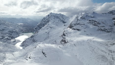 Vuela-Sobre-La-Toma-De-Un-Majestuoso-Pico-Montañoso-En-Los-Alpes-Desde-Un-Dron-En-Invierno-En-Un-Día-Soleado