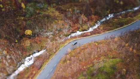 An-aerial-view-of-a-car-driving-down-the-narrow-serpentine-road-above-the-Geiranger-fjord