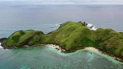 green-mountain-hills-of-Bukit-Merese-in-Lombok-surrounded-by-turquoise-water,-aerial