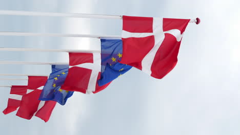 Denmark-and-EU-flag-on-flagpole-waving-on-moody-cloudy-day
