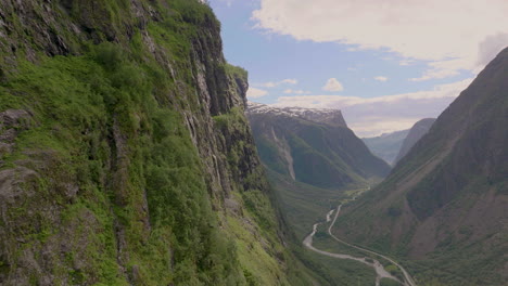 Magical-Gudvangen-Valley,-Aerial-Drone-flies-past-lush-green-cliffs-over-river