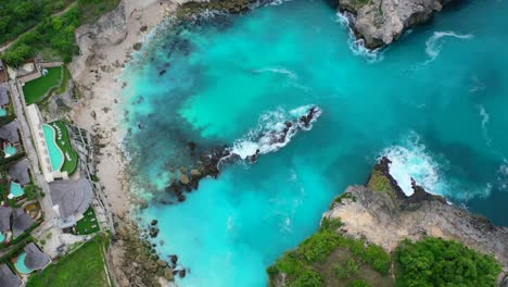 turquoise-waves-crashing-on-rocky-beach-at-Blue-Lagoon-at-Nusa-Ceningan-Island,-aerial-top-down-view