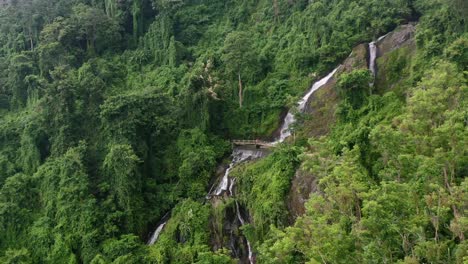 waterfall-on-a-mountain-jungle-rock-in-Lombok-Indonesia-on-cloudy-day,-aerial