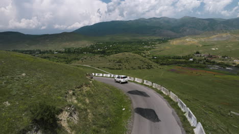 Lone-White-Car-Driving-Along-Cliffside-Mountain-Road-With-Concrete-Barrier-Outside-Aspindza-District-In-Georgia