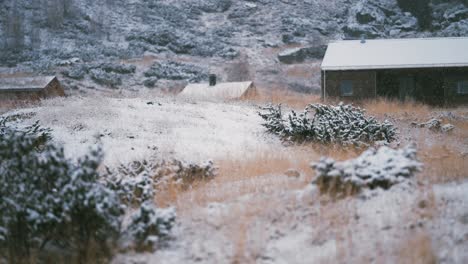 Leichter-Erster-Schnee-Fällt-Auf-Das-Verwelkte-Gras,-Die-Steine-Und-Die-Dächer-Der-Holzhütten