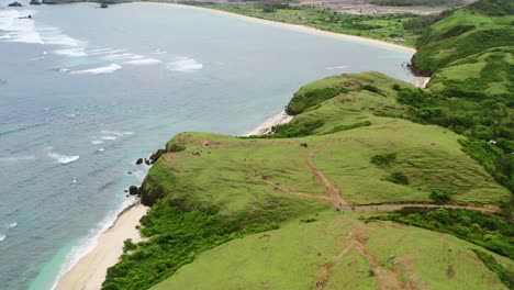 Grüne-Wiese-Und-Weißer-Sandstrand-Bei-Bukit-Merese-Lombok,-Umgeben-Von-Ozean,-Antenne