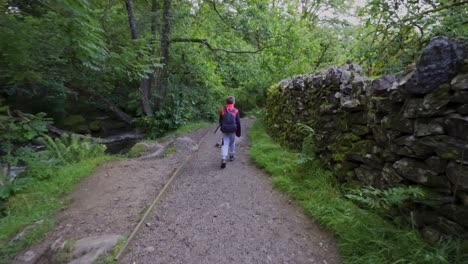 Slow-motion-footage-of-a-young-boy-hiking-down-a-countryside-pathway-with-a-drystone-wall-to-the-right