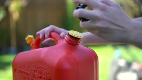 Close-up-of-caucasian-hand-opening-red-gasoline-canister-outdoors