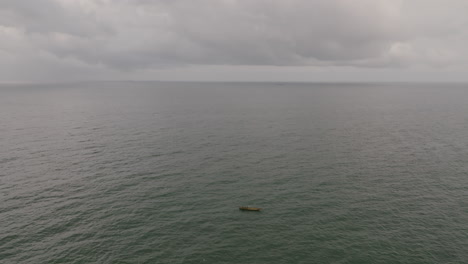 Aerial-footage-of-a-single-boat-on-the-vast-ocean,-fishing,-just-outside-of-Freetown,-Sierra-Leone