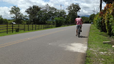 Car-and-a-bicycle-passing-by-on-a-road-in-the-countryside-of-Sierpe,-Costa-Rica