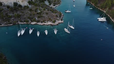 Drone-orbit-view-of-a-wild-secluded-beach-at-the-coastline-of-Brac-Island,-Croatia,-Adriatic-Sea,-where-luxury-sailing-boats-are-anchored