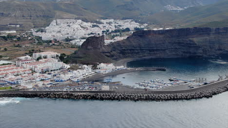 Toma-Aerea-Sobre-El-Puerto-De-Agaete-Apreciando-Los-Barcos-En-El-Muelle-Y-Las-Casas