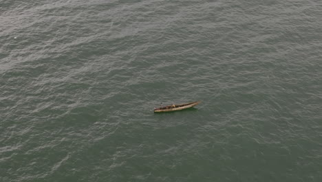 Close-aerial-footage-of-a-small-fishing-boat-rocking-the-waves-of-the-ocean-off-the-coast-of-Sierra-Leone