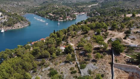 Aerial-revealing-shot-of-popular-anchorage-location-Bobovisca-showcasing-the-beautiful-coastline-of-Brac-Island,-Croatia,-Adriatic-Sea-and-a-variety-of-boats