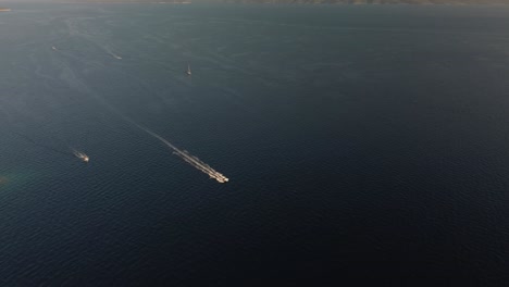 Drone-orbit-shot-of-speed-boats-navigating-between-Hvar-and-Brac-Islands-along-the-scenic-coastline,-Croatia,-Adriatic-Sea
