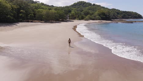 Young-Beautiful-Woman-Walking-Alone-Along-The-Wet-Sand-In-A-Black-Bikini-At-The-Beautiful-Playa-Real,-Guanacaste-Province