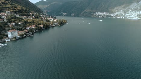 Aerial-opening-of-famous-lake-como-in-italy-showing-boats-and-the-shoreline-of-Torriggia-with-the-alps-mountains-in-the-background