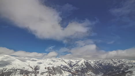 High-altitude-time-lapse-of-clouds-flying-over-white-snowy-mountain-range---picturesque-Alpine-nature-scene