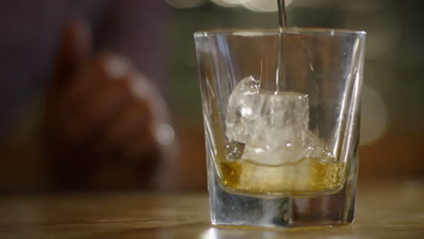 Zeitlupenaufnahme-Des-Gießens-Von-Whiskey-In-Glas-Mit-Eiswürfeln