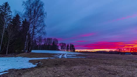 Time-Lapse-of-vibrant-sunset-at-countryside,-snow-and-ice-melting-meadow,-End-of-Winter-concept