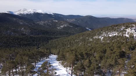 Spectacular-aerial-view-of-the-Navacerrada-ski-area-in-Madrid,-Spain,-with-the-Guadarrama-mountain-range-in-the-background-and-people-skiing-in-the-foreground
