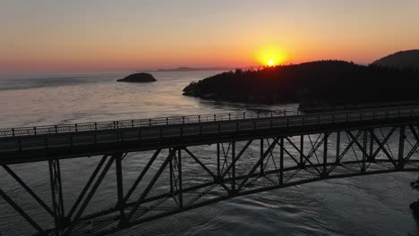 Aerial-view-of-cars-driving-over-Deception-Pass-at-sunset-on-a-summer-evening