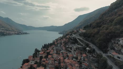Beautiful-aerial-of-flying-slowly-along-lake-como-shore-at-Torriggia-showing-houses-roads,-alp-mountains---moody-cinematic