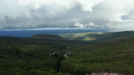 Stunning-aerial-drone-dolly-out-shot-of-rolling-green-hills,-a-windy-river,-and-an-overcast-sky-in-the-famous-and-beautiful-Chapada-Diamantina-National-Park-in-Northeastern-Brazil