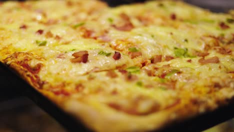 Closeup-of-cheesy,-square-pan,-combination-pizza-with-ham-and-green-bell-peppers