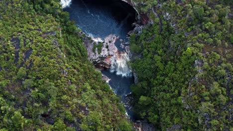 Aerial-drone-wide-bird's-eye-slow-rotating-shot-of-the-small-waterfall-at-the-bottom-of-the-Devil's-Pit-surrounded-in-the-beautiful-Chapada-Diamantina-National-Park-in-Northeastern-Brazil