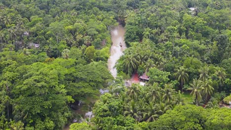 Drone-flyover-dense-jungle-crossing-by-muddy-river,-Amazonia-Forest,-Lush-vegetation
