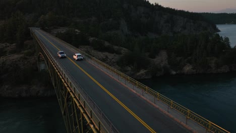 Drone-shot-of-cars-passing-over-Deception-Pass-State-Park's-bridge-at-sunrise
