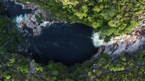 Aerial-drone-wide-bird's-eye-shot-of-the-stunning-Devil's-Pit-waterfall-surrounded-by-rocks-and-jungle-foliage-in-the-beautiful-Chapada-Diamantina-National-Park-in-Northeastern-Brazil