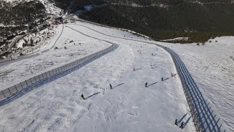 Aerial-view-of-a-group-of-people-descending-a-hill-practicing-skiing,-in-the-Navacerrada-ski-station,-Madrid,-Spain