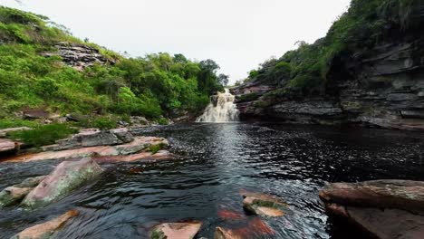 Extreme-wide-action-camera-tilting-up-shot-from-on-rocks-revealing-the-stunning-Devil's-Pit-waterfall-in-the-beautiful-Chapada-Diamantina-National-Park-in-Northeastern-Brazil-on-an-overcast-day