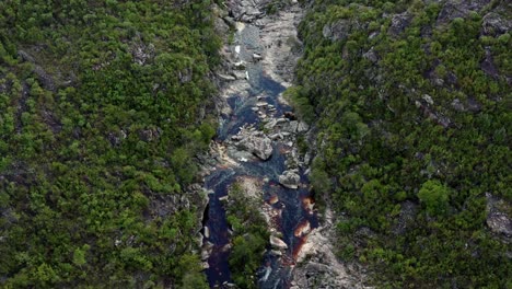 Aerial-drone-top-down-passing-shot-above-an-incredibly-stunning-rocky-and-windy-river-leading-to-the-Devil's-Pit-on-a-hike-in-the-beautiful-Chapada-Diamantina-National-Park-in-Northeastern-Brazil