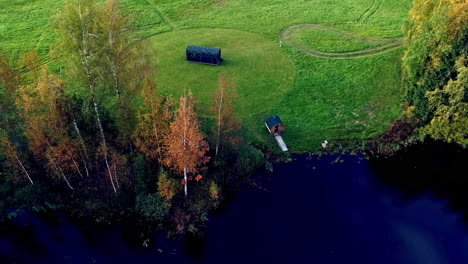 Aerial-top-down-shot-of-wooden-house-and-private-barrel-sauna-in-nature-at-lake-shore-in-summer
