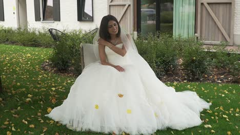 Bride-sitting-on-a-chair-in-the-garden-with-her-wedding-dress-on