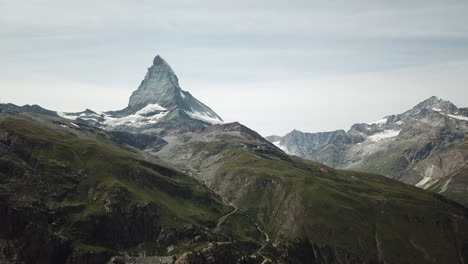 Grasbewachsener-Gipfel-Der-Schweizer-Alpen:-Blick-Auf-Den-Cervin-Mit-Seinen-Scharfen-Felsen-Und-Seinem-Schnee,-Hochgelegener-Berggipfel,-Drohne-Luftaufnahme,-Natur