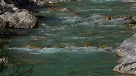 Mountain-river-with-crystal-emerald-water-streaming-through-stones,-beautiful-background