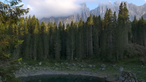 Slow-Dolly-Revealing,-Establishing-Footage-Of-Charming-Teal-Pond-With-Rock-Mountains-In-The-Background-In-The-Dolomites