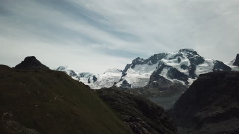 Drone-view-of-the-summits-in-the-Swiss-alps,-snow-in-high-altitude,-cloudy-sky,-mountains