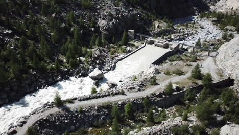 Drohnenluftaufnahme-Eines-Bergbaches-In-Der-Nähe-Eines-Tannenwaldes-In-Einem-Tal-Der-Schweizer-Alpen