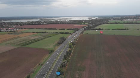 Aerial-Drone-View-Showing-Of-Busy-Hungarian-Highway,-Beautiful-Lake-In-The-Background
