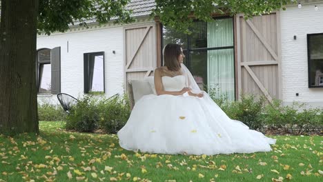 Schöne-Braut-In-Ihrem-Hochzeitskleid,-Das-Im-Garten-Sitzt